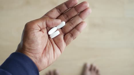 la mano sosteniendo pastillas blancas