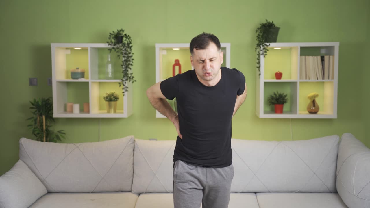 Man suffering from hernia, neck and lower back pain, backache at home.
