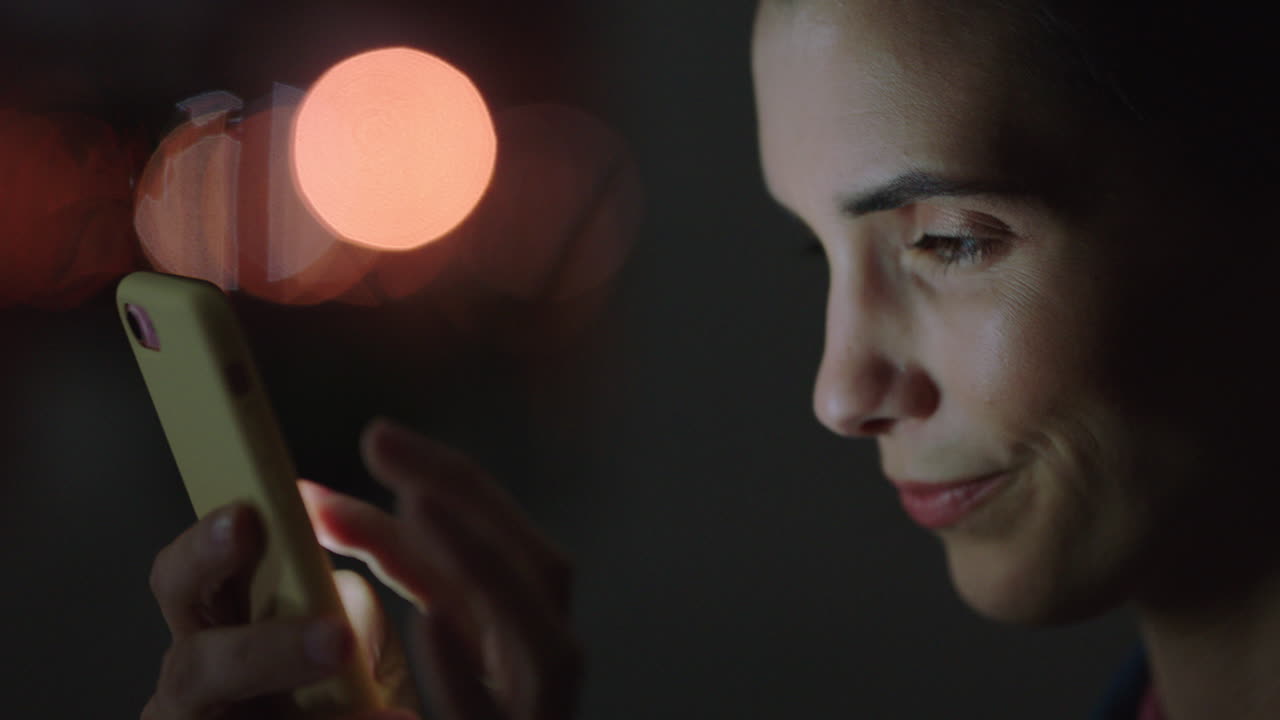 스마트폰을 사용하는 아름다운 여성 온라인 브라우징 긍정적인 메시지를 온라인으로 읽는 소셜 미디어 커뮤니케이션 문자 메시지를 즐기는 밤 늦게 일하는