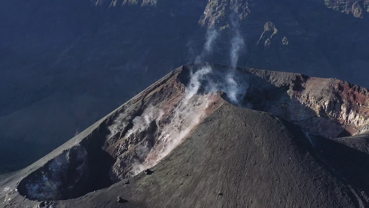 cono de cráter activo humeante del volcán monte rinjani en indonesia, toma de órbita aérea