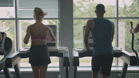 Rear-view-of-caucasian-female-monitor-and-an-athletic-african-american-man-in-the-gym.