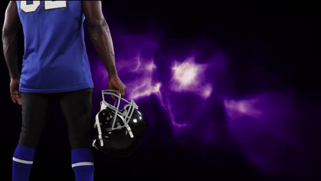 american football player holding helmet over light trails