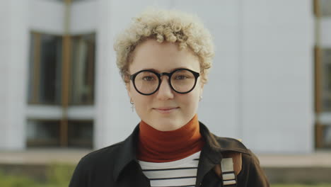 portrait of a young woman with curly blonde hair and glasses