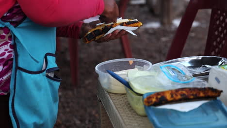 vendedora que prepara comida callejera de plátano a la parrilla para el cliente en san cristobel en las galápagos