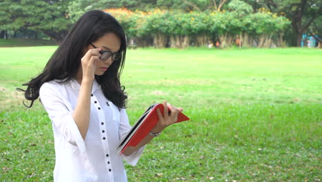 woman student reading book in university park