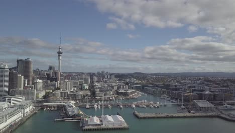 drone flying away from sky tower and showing cbd and the port of auckland queens wharf