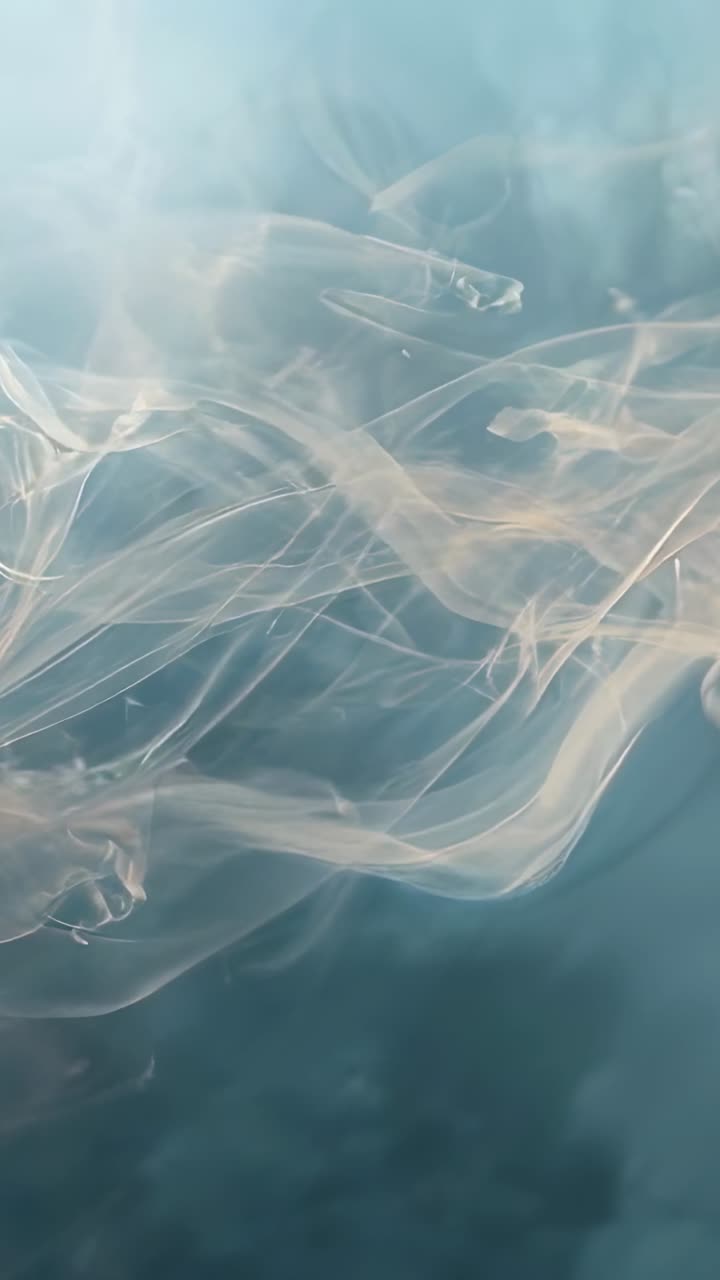 Video verticale: camera fissa, nastri impalpabili che fluttuano su uno sfondo color ottanio sotto una luce soffusa