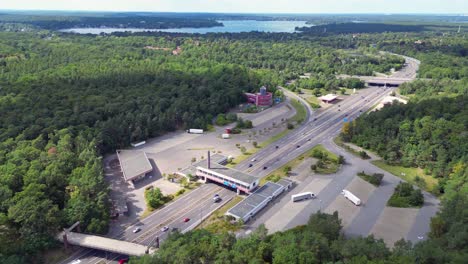 cars driving on a freeway interchange surrounded by forest leading to a lake on a cloudy day. nice aerial view flight descending drone