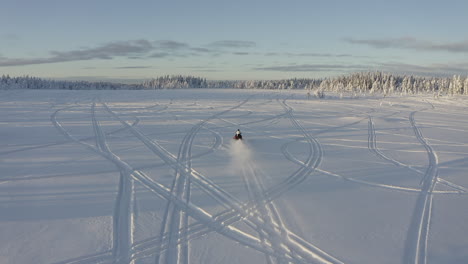 Luftdrohnenaufnahme-Eines-Schneemobilfahrers,-Der-Schnell-Auf-Einem-Tiefschneefeld-Fährt