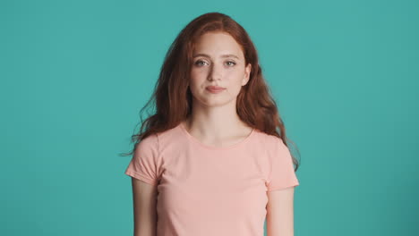 redheaded girl looking at camera on turquoise background.