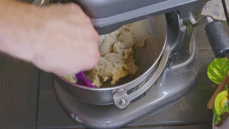 raspando los lados del cuenco después de agregar ingredientes y mezclar la masa