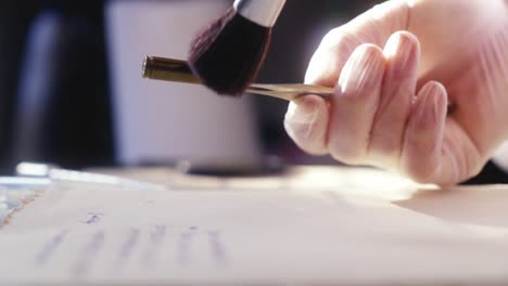 a forensics expert examines the bullet, working with a brush and magnifying glass