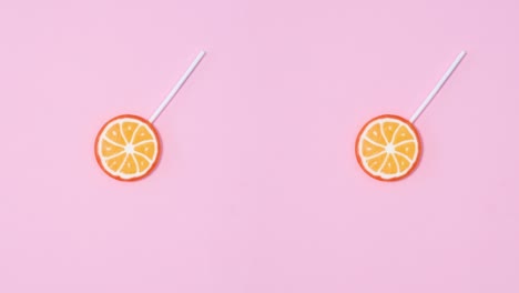 las piruletas frutales giran en círculo y cambian sobre un fondo rosa pastel.