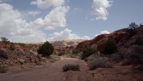 handheld shot of a stunning wide landscape shot of a dry desert hiking path surrounded by sage brush, large red and pink rocks near the popular tourist destination of buckskin gulch in southern utah