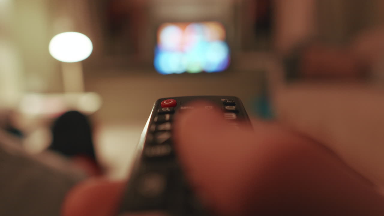 Accensione della TV con il telecomando da una prospettiva seduta, ambiente interno calmo