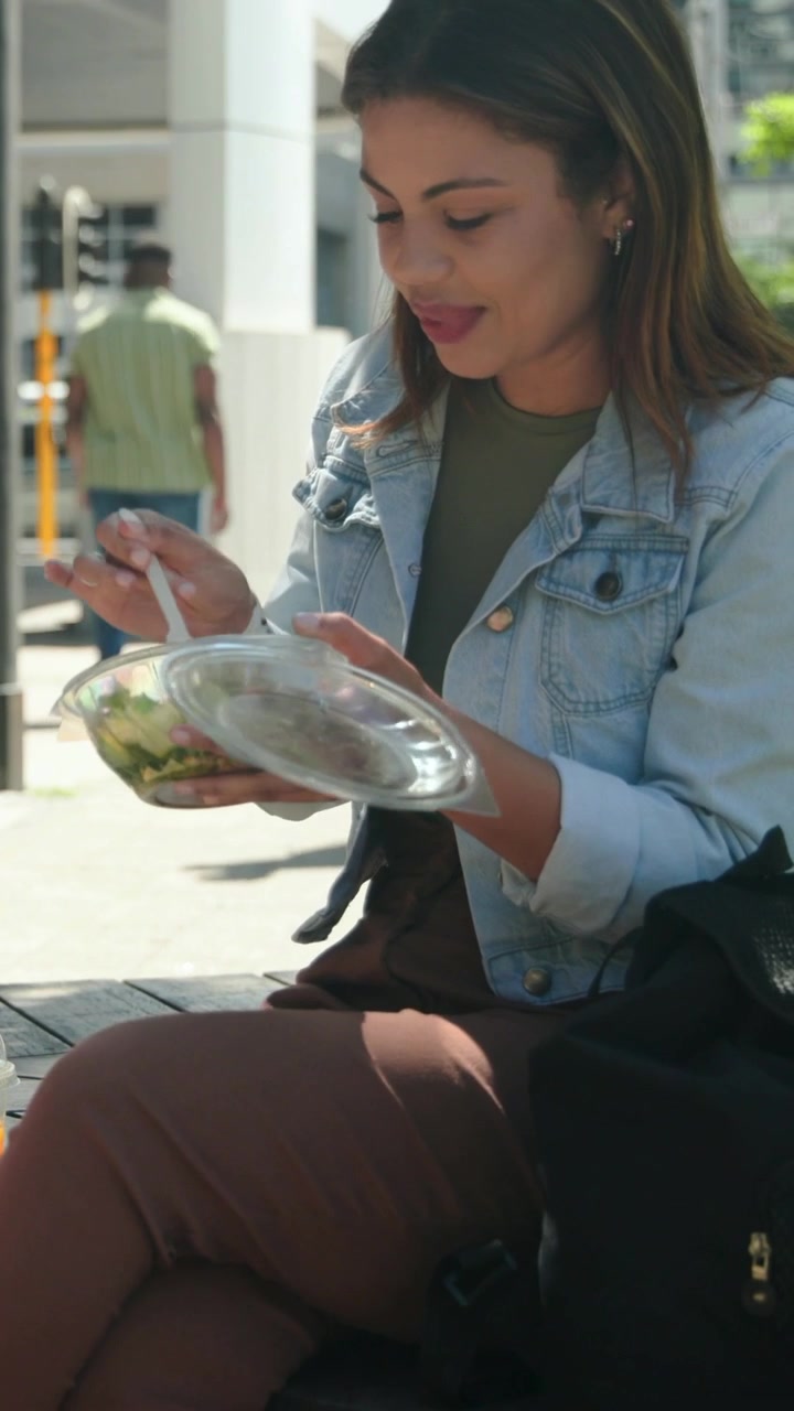 Woman glancing left, opening salad bowl for lunch in plaza, revealing animated food tags above bowl