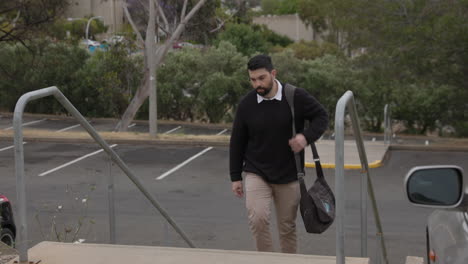 male office worker walks from a car parking lot up stairs to the office during the day