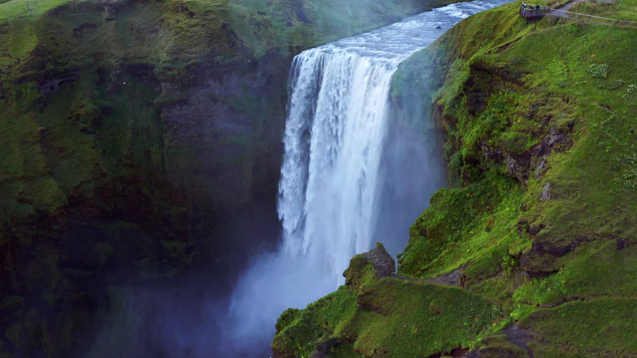 majestuosas cascadas de skogafoss en un acantilado con gente en la plataforma de observación en el sur de islandia