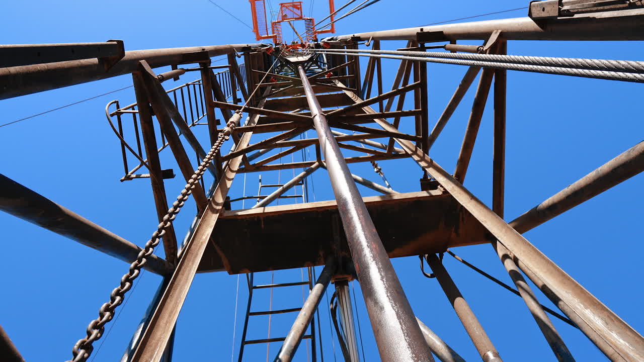 Standing under and looking up at the high tower of a drilling site. Equipment used for resources production.