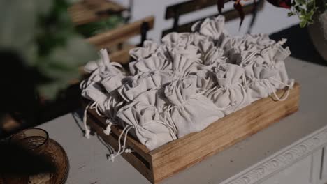 close up of fabric wedding favor bags arranged neatly in a wooden tray