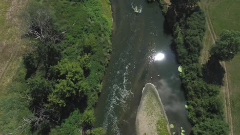 Reflejo-Del-Sol-En-El-Agua-Del-Río-Que-Fluye-Entre-Los-Campos-Rurales-En-Verano