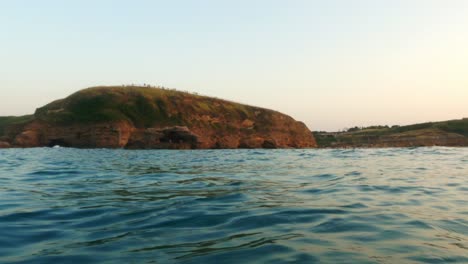 Low-angle-water-surface-pov-of-Punta-Aderci-Abruzzo-natural-reserve-seen-from-sailing-boat-at-sunset,-Italy