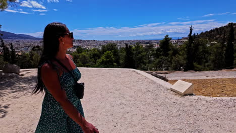 hermosa chica con cabello negro y gafas de sol visitando la acrópolis de atenas