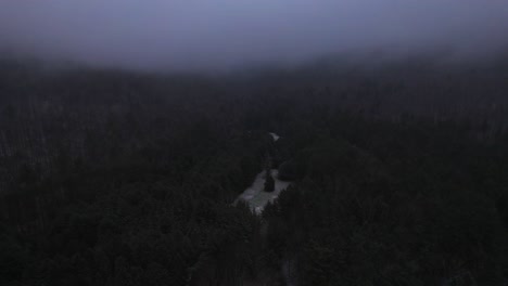 aerial drone video footage of nightfall in the snowy and foggy appalachian mountains during winter, in the catskill mountains sub-range