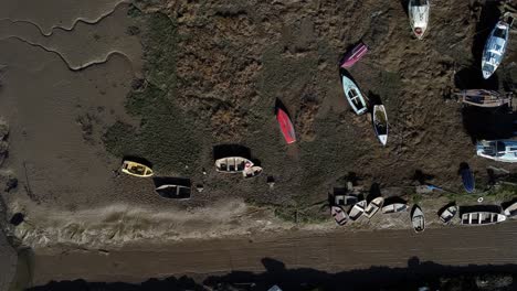 stranded fishing boats shipyard in marsh mud low tide coastline aerial birdseye view