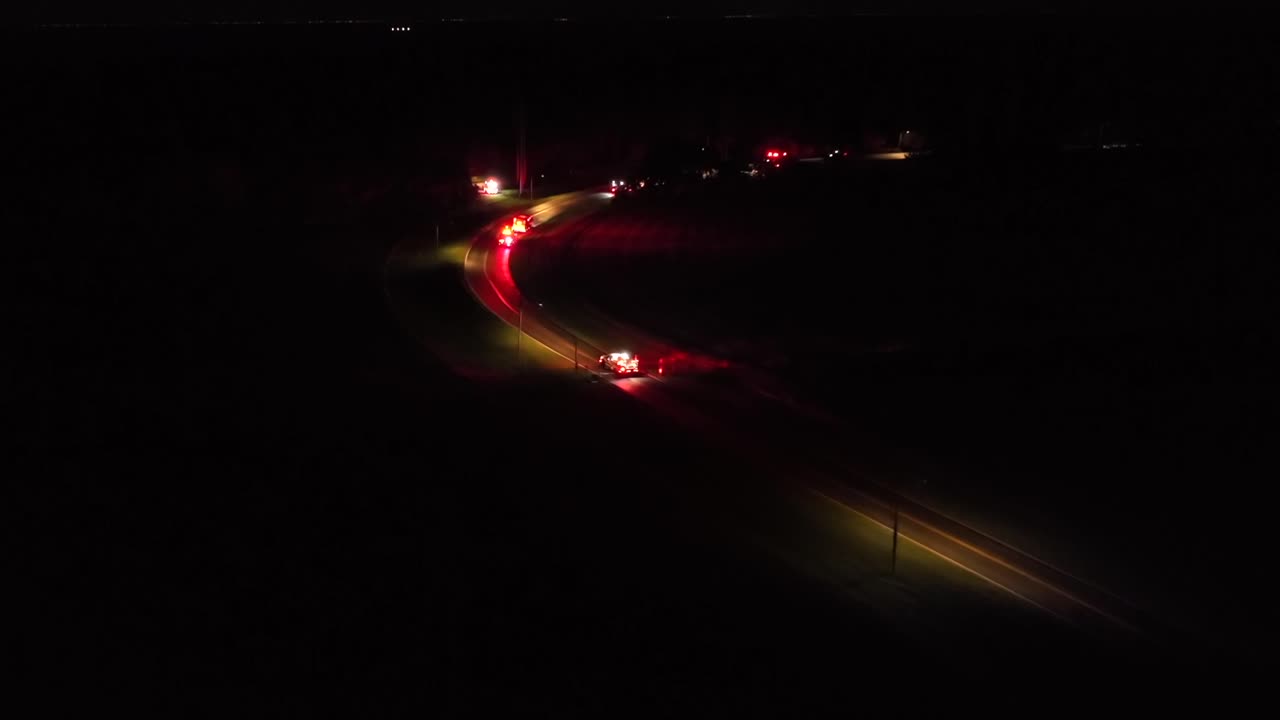 Aerial establishing shot of car accident on american highway at night. Flashing red lights of fire truck,arriving crash site on road. Aerial wide shot. Dangerous traffic scene in USA. Call 911 and 112