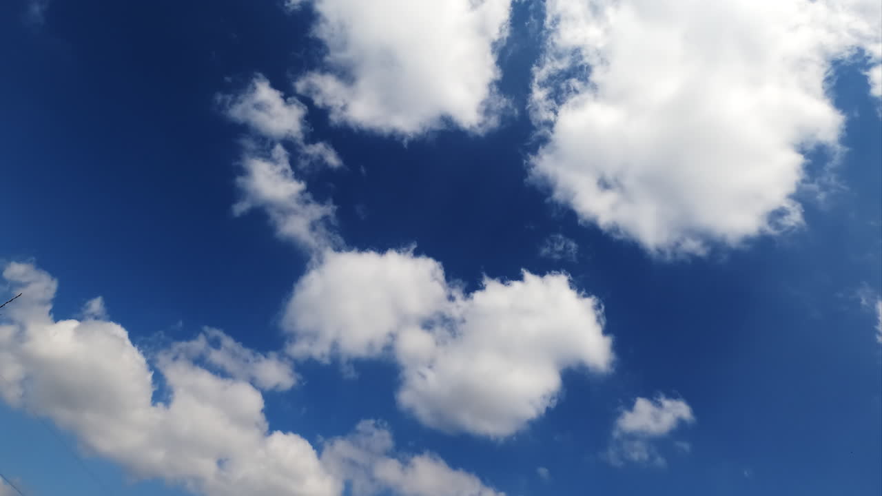 White cotton clouds floating fast in the sky. Blue summer sky with beautiful clouds. Time lapse.