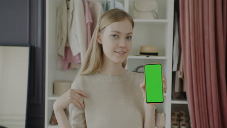 woman holding a phone with a green screen in a clothing store