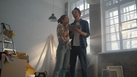 familia joven viendo la tableta en el interior. pareja usando la tableta para ideas de reparación del hogar.