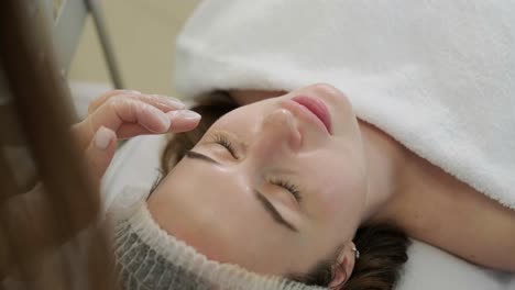 cosmetologist doing face treatment and applying face mask