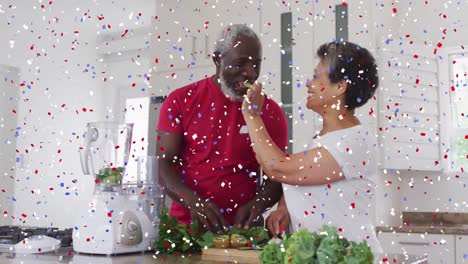 confetti falling against african american senior woman feeding chopped fruits to her husband