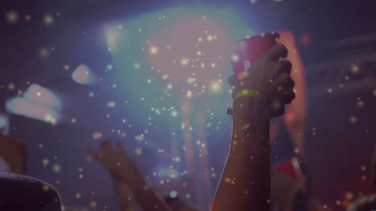 Braccio che alza un bicchiere rosso a un concerto, MC che alza, LED che pulsano incitando la folla, glitter che fluttuano sulla folla