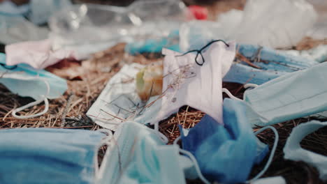 debris from medical masks and plastic lies on the ground in the forest