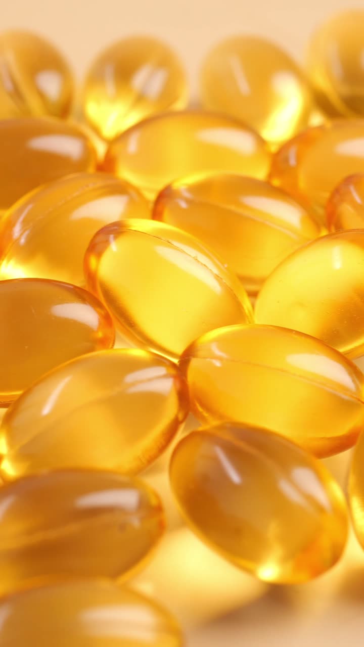 Primo piano di capsule vitaminiche giallo dorato in rotazione