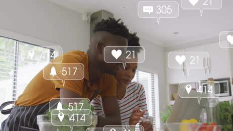social media notifications animation over couple using laptop in kitchen