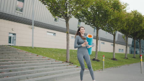 mujer haciendo ejercicio al aire libre con una alfombra de yoga y una botella de agua