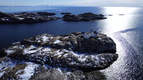 Slow-orbit-of-historic-Henningsvaer,-on-a-bright-sunny-winter-day,-Norways-oldest-fishing-village,-with-light-house-and-football-pitch