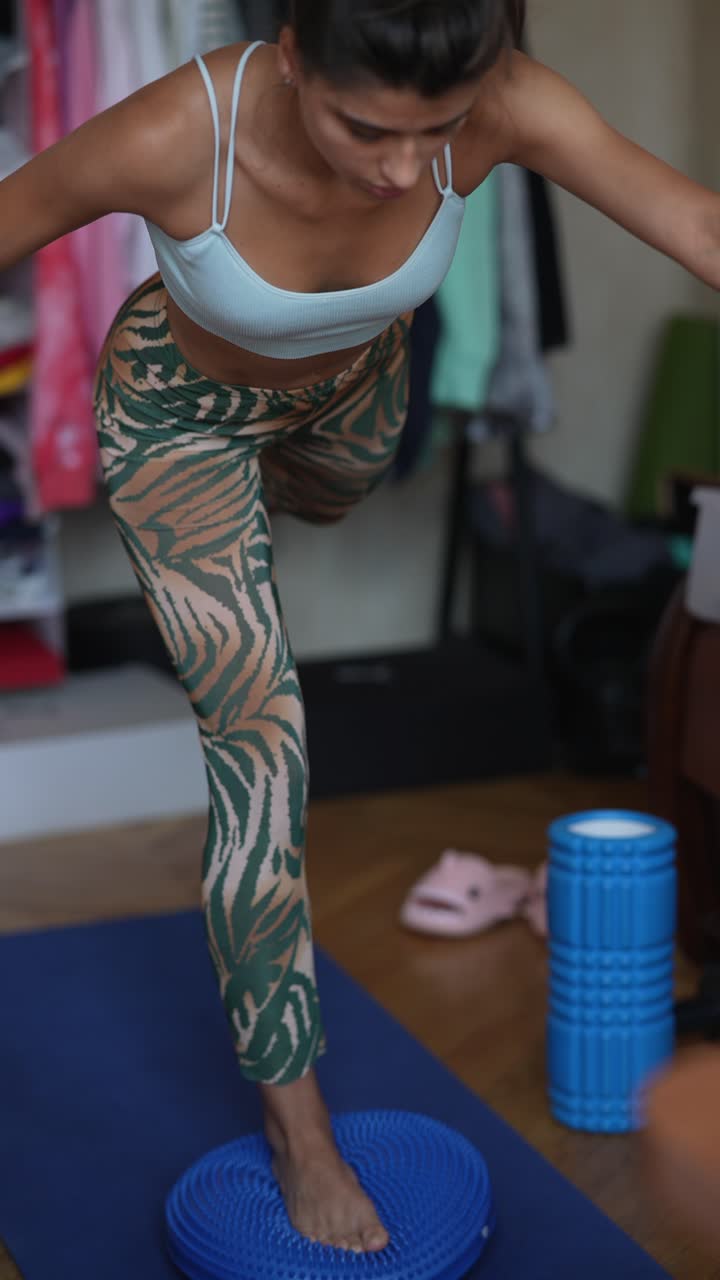 mujer practicando la postura de equilibrio de yoga en casa