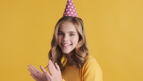 una adolescente caucásica con un sombrero de fiesta y riendo.
