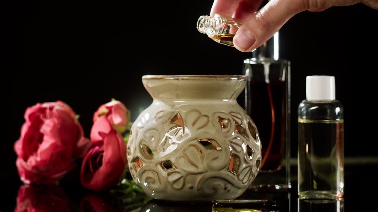 Menuangkan Minyak Esensial ke dalam Diffuser Aromaterapi Keramik dengan Bunga