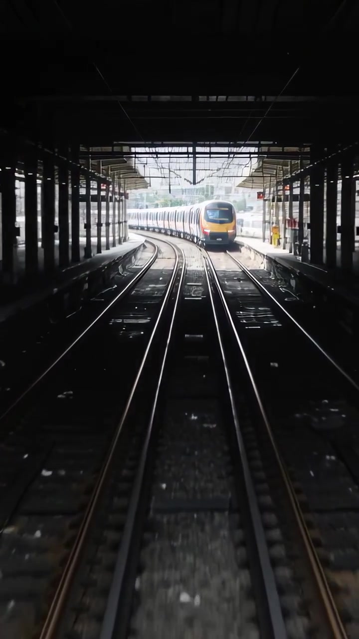 Vertical video: Approaching train moving along track after signal stopping at platform yellow front
