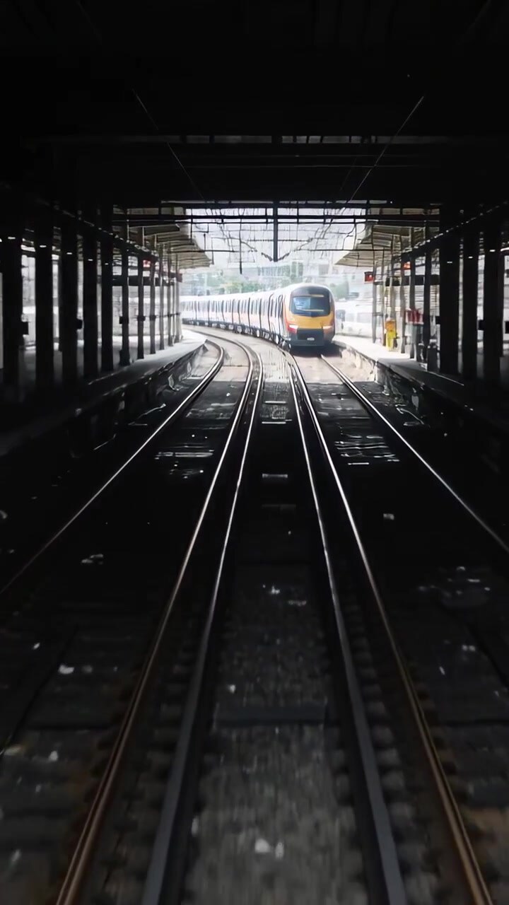 Vertical video: Approaching train moving along track after signal stopping at platform yellow front