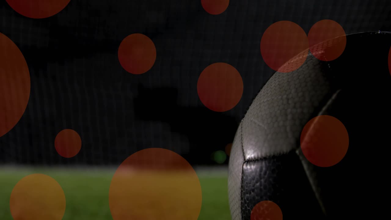 Atacante chutando bola de futebol em direção à rede do gol sob os holofotes para marcar enquanto o goleiro mergulha