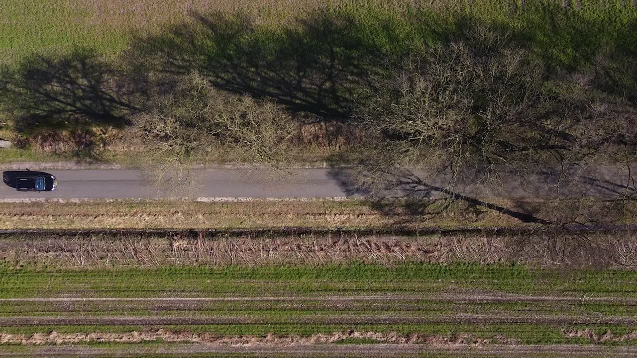 검은색 자동차가 시골길을 가로질러 운전한다