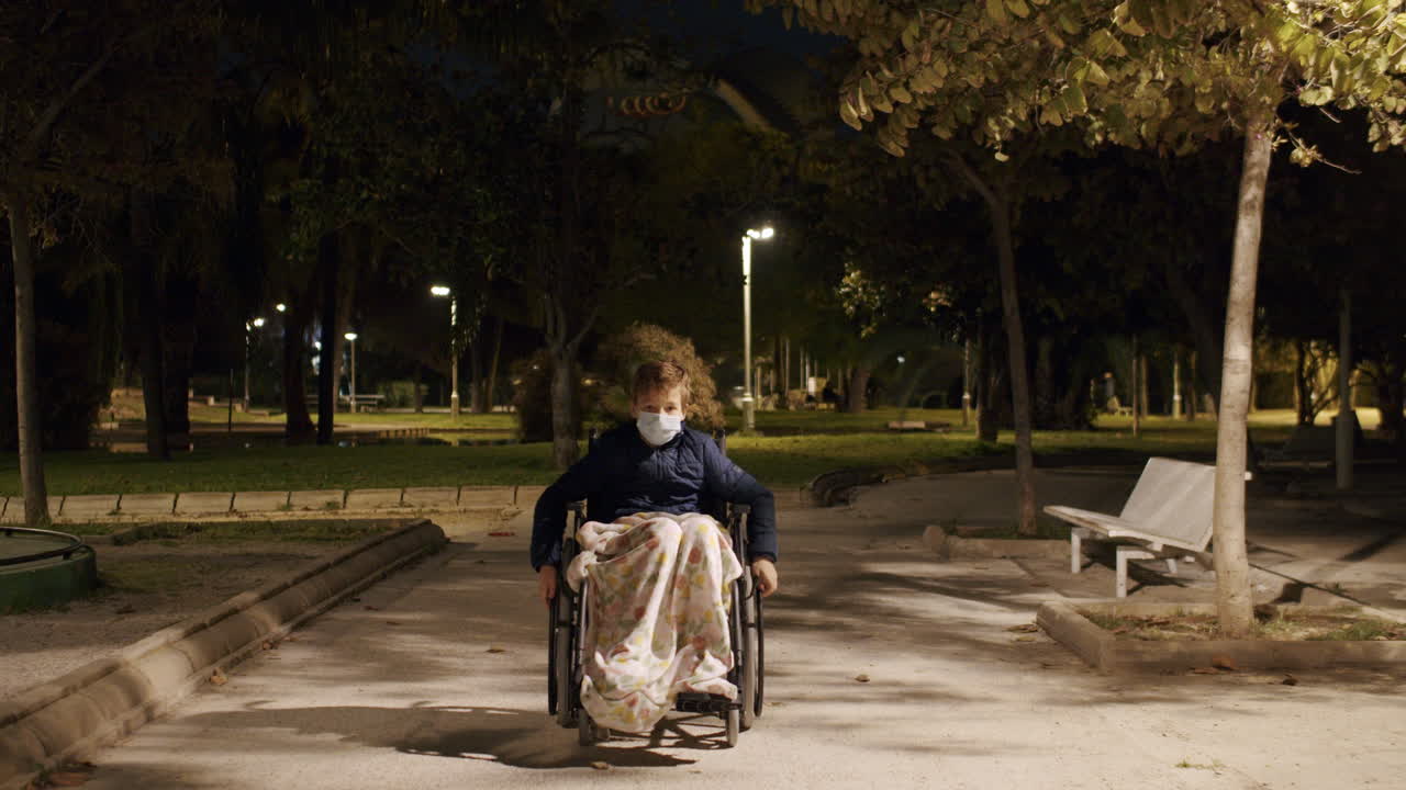Handicapped boy in wheelchair in the park in late evening