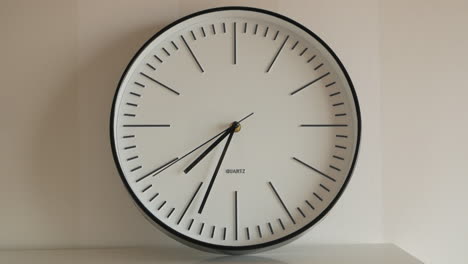 Broken-Clock-On-Top-Of-Table-Against-White-Wall,-Close-Up-Shot